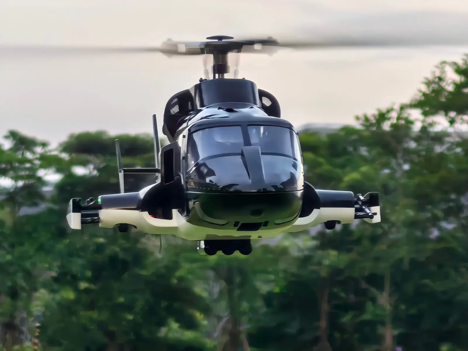 FLISHRC Airwolf V2 Pro 500-size scale RC helicopter in flight, seen from the front against trees