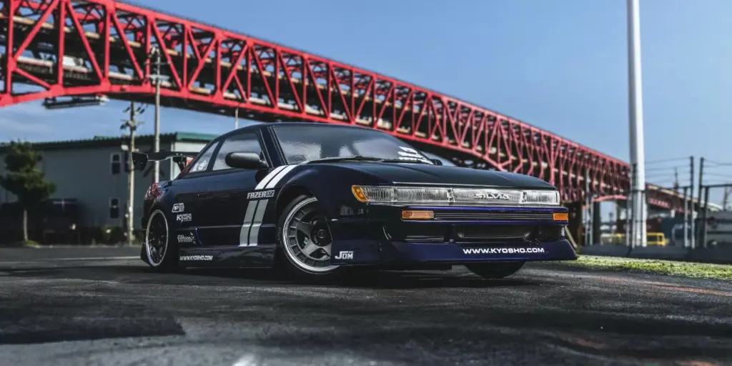 Kyosho Fazer D2 Nissan Silvia S13 Tuned in purple parked beneath a red steel bridge